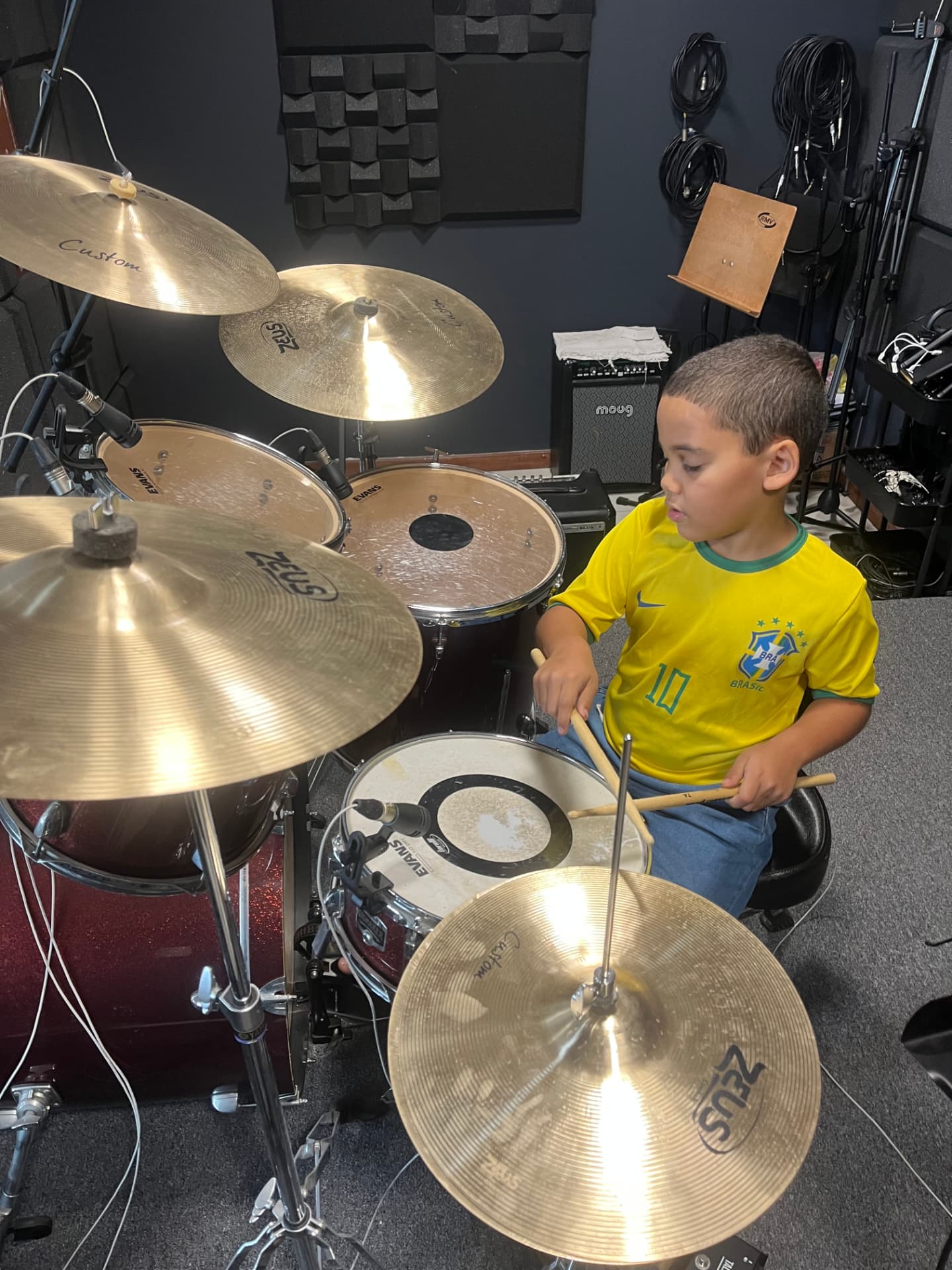 Menino tocando bateria no estúdio durante aula do Projeto PHIARA